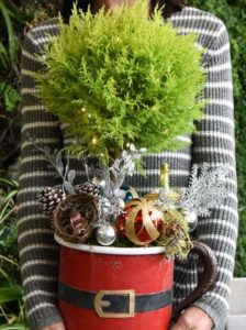 cypress topiary tree with LED microlights, holiday ornaments, natural winter elements of pine cones, bird nest, mossy branch designed in a metal Santa mug