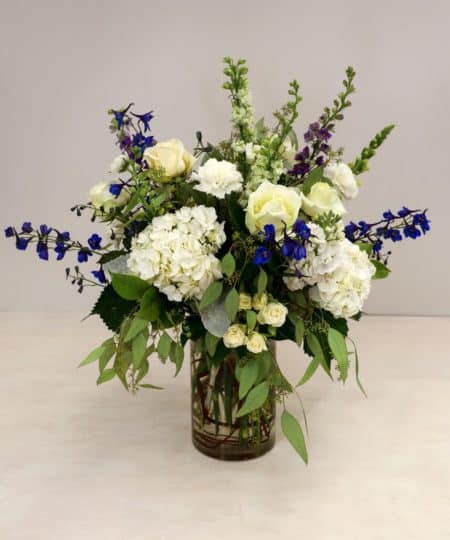 This heavenly arrangement of white flowers with blue accent blooms sends a message of blissful love.